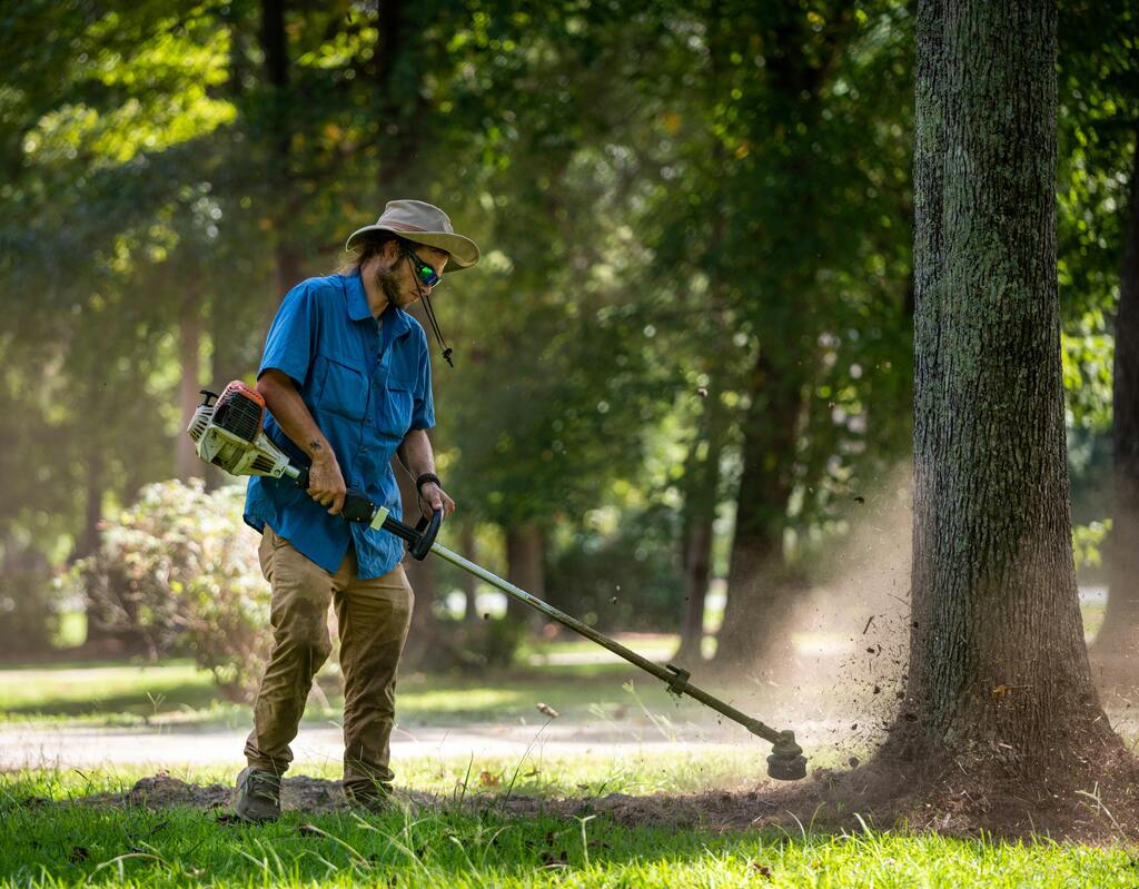 Gardener trimming grass with a power trimmer